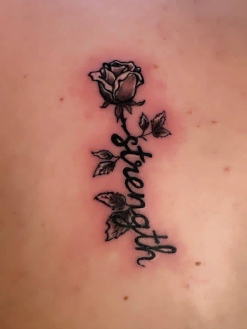 Tattoo by Jake Brewer, the word Strength in script with a rose