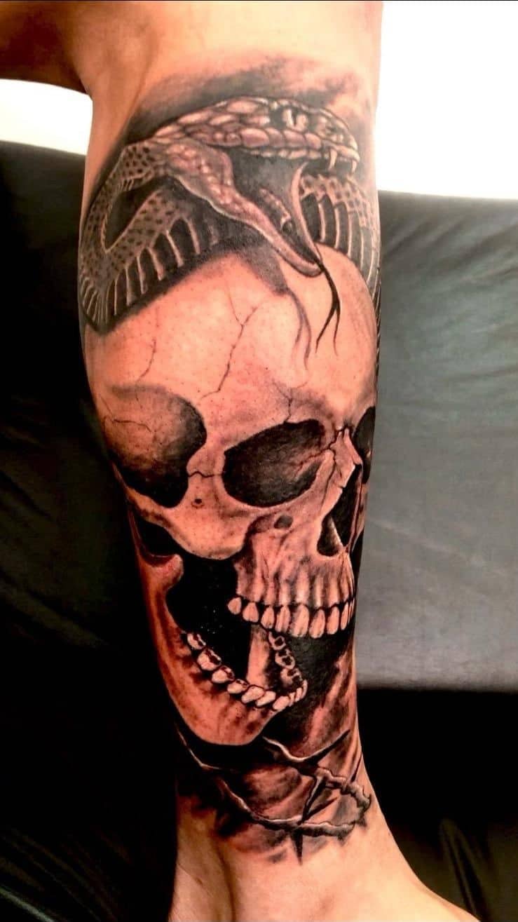 Tattoo by Ricardo Mendes, skull with a snake coiled over it, in black and grey