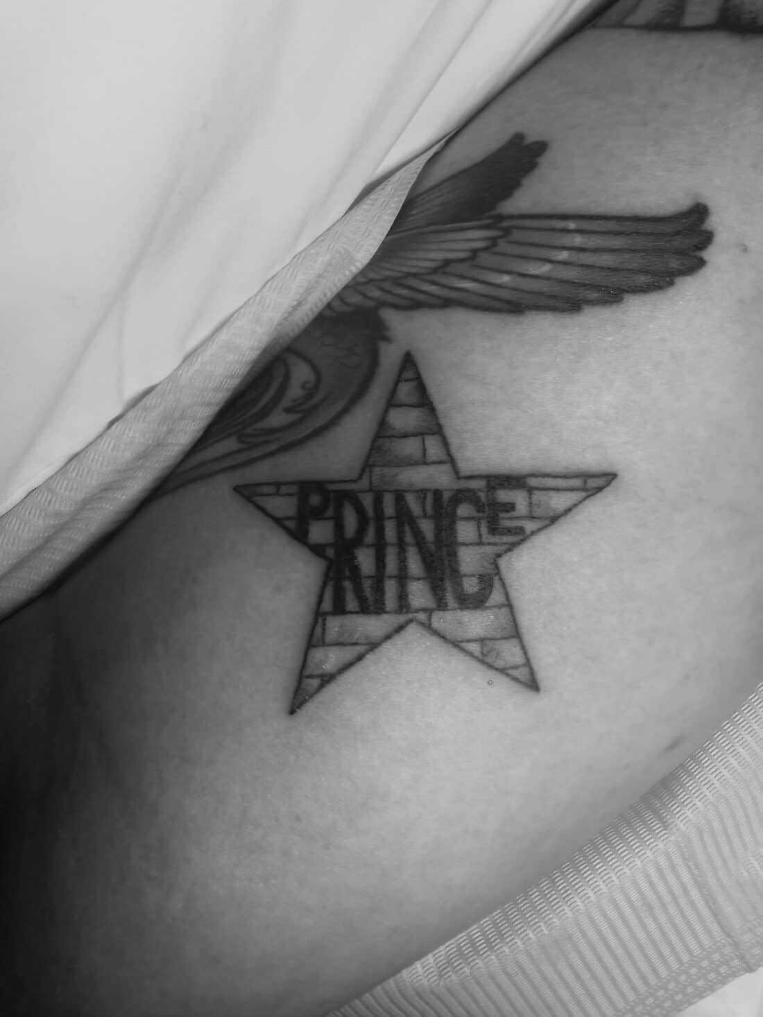 Tattoo by Apollonia Ink in Barrie, star with Prince lettering and a feathered wing, in black and grey