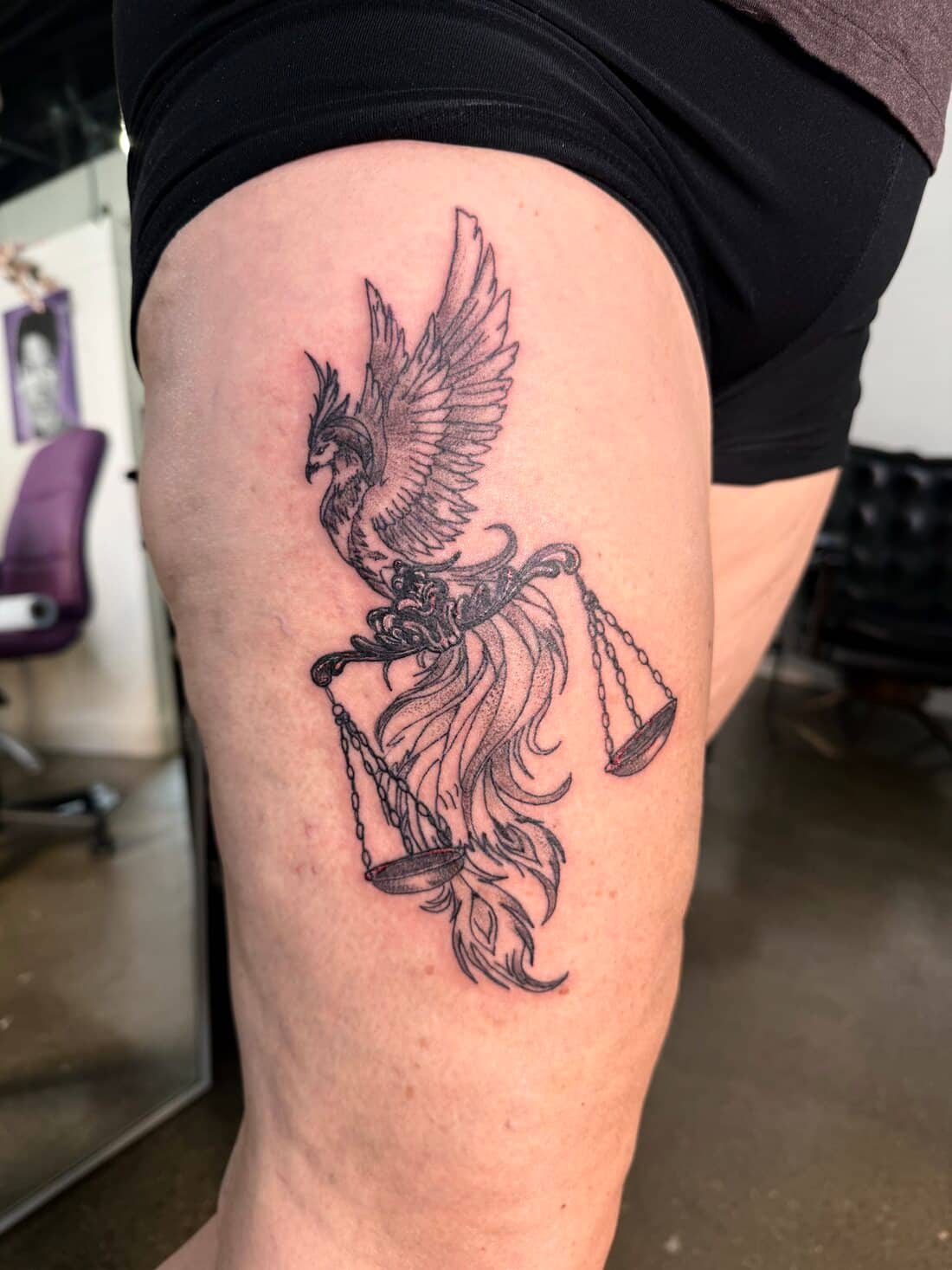 Tattoo by Apollonia Ink in Barrie, phoenix carrying the scales of justice on a thigh, in black and grey