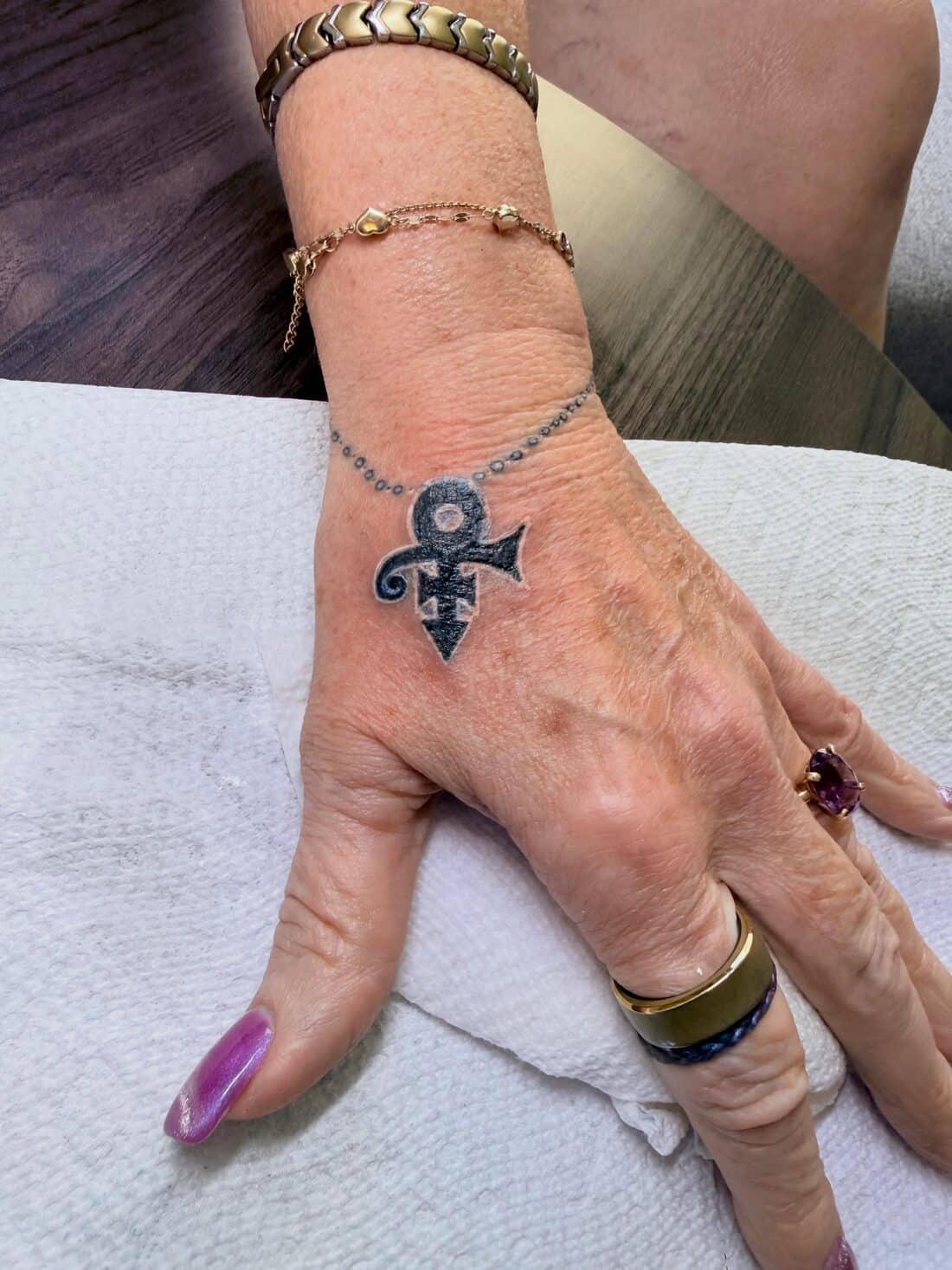 Tattoo by Apollonia Ink in Barrie, small Prince love symbol on the back of a hand